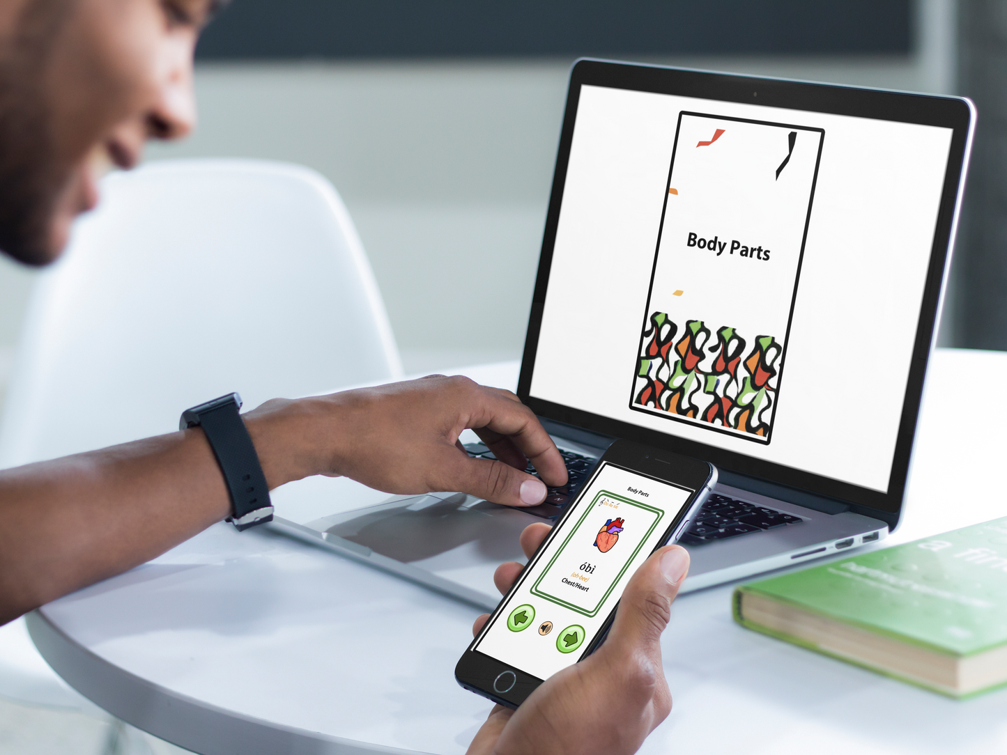 Person using a laptop and smartphone with Igbo interactive edition on  both screens